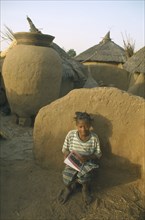 BURKINA  FASO, Bisaland, Sigue Voisin, Near Garango.Young girl called Mariam sat against wall doing