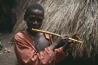 SIERRA LEONE, Kambia, Young boy playing home made flute.
