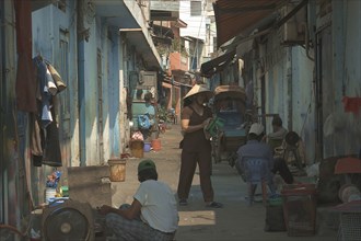 VIETNAM, South, Ho Chi Minh City, View down a side street with a woman wearing a conical hat and