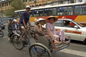 VIETNAM, South, Ho Chi Minh City, Passengers riding in a cyclo in heavy traffic down a busy street