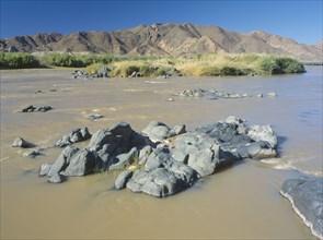 NAMIBIA, South, Orange River, Rocks in the  water in The Orange River further west after being