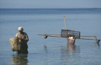 PHILIPPINES, Panglao, Woman collecting shellfish at Alona Beach on island off the coast of Bohol.