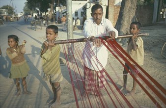 INDIA, People, Work, Family working together.  Two boys supporting loom for father to weave.