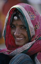 INDIA, People, Head and shoulders portrait of a smiling woman wearing pink sari with flower print