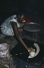 SUDAN, Cooking, Dinka tribeswoman making flatbread inside hut.