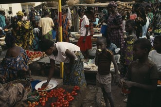 MALI, Kayes, Busy market scene with brightly dressed women and children amongst food stalls.