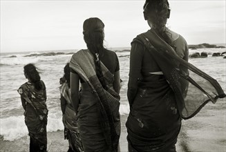 INDIA, Tamil Nadu, Kanyakumari, "Orphanage workers enjoy a day out by the sea, backs to camera."