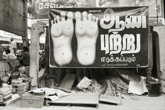 INDIA, Tamil Nadu, Madurai, Street reflexologist's open air clinic. Poster of bottom of feet.