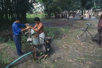 INDIA, West Bengal, Priming a modified irrigation pump with a hand pump.