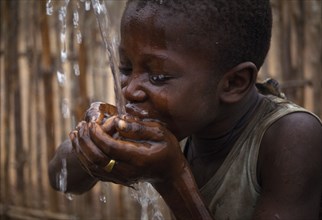 SIERRA LEONE, Water, Child cupping his hands together drinking well water