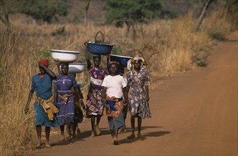 GHANA, North, Women walking to market carrying bowls on their heads.