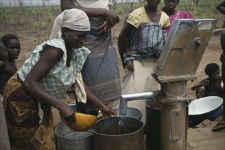 GHANA, North, Chereponi, Women collecting water from well water pump.