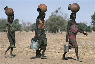 SUDAN, Habila Settlement, Chadian refugee women collecting water from well in camp near El Geneina.