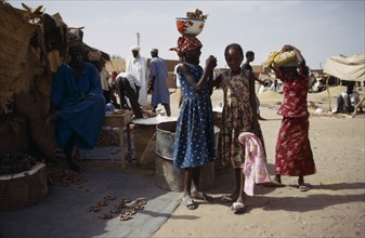 NIGER, People, Young girls standing outside market stall belonging to their father.