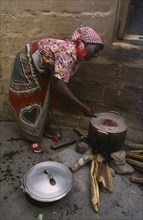 MOZAMBIQUE, People, Cooking, Woman refugee cooking beans in pot over open fire.