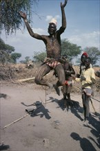 SUDAN, Tribal People, Dinka tribesman with his body painted with ash leaping in to air with his