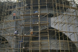GHANA, Accra, Construction workers on scaffolding surrounding new bank building.