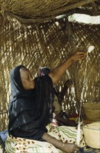 CHAD, N Djamena, Woman spinning cotton inside straw hut