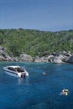 THAILAND, Similan Islands, Ko Bangu, Snorkelers in the water next to a small motor boat near the