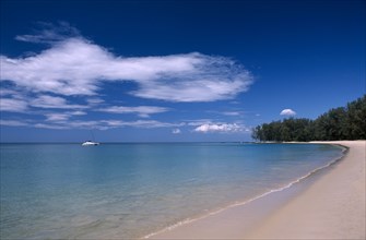 THAILAND, North Phuket, Naiyang Beach, View along the empty sandy beach with a single boat in the