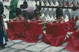 SOUTH KOREA, Religion, Buddhism, Confucian Rites Orchestra. Line of men in red robes sat on ground