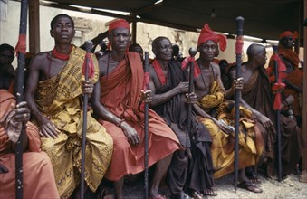 GHANA, Tribal People, Ashanti Akan tribal members holding staffs wrapped with red cloth attending