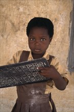 GHANA, Education, Portrait of pupil from primary school in village near Accra holding small