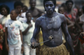 GHANA, Accra, Man holding knife to his stomach during juju ceremony to summon ancestor spirits.