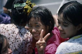 MYANMAR, Mandalay, Young girl smiling and making the V peace sign with fingers amongst other girls