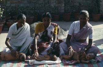 INDIA, West Bengal, Calcutta, Women massaging their babies.