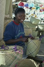 MADAGASCAR, Antananarivo, Girl making rafia baskets on market stall.