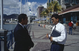 MAURITIUS, Port Louis, Two businessmen in conversation on the town waterfront.