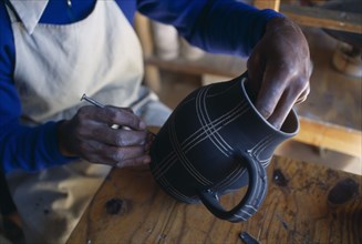 MALAWI, Dedza, Dedza Potteries producing Fair Trade goods for export.  Craftsman decorating pot.