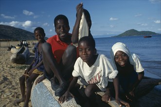 MALAWI, Cape Maclean, Lake Malawi, Group of children sitting on boat on lake shore.