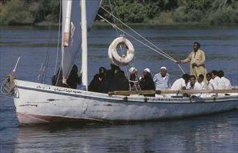 EGYPT, Nile Valley, Aswan, Felucca sailboat full of passengers on the River Nile.