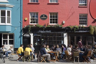 ENGLAND, East Sussex, Brighton, Fitzherbert’s public house in New Road with people sat outside.