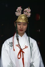 JAPAN, Honshu, Osaka, Portrait of a miko or shrine maiden at small Shinto temple in Osaka.