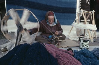 TUNISIA, Tozeur, Elderly man spinning wool for rug making.