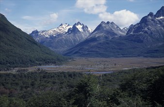 ARGENTINA, Patagonia, Tierra del Fuego, View across green forest towards partially snow capped