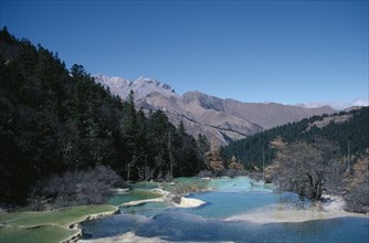 CHINA, Sichuan Province, Huanglong, View across pools formed by calcium carbonate in water towards