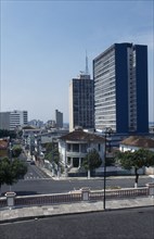 BRAZIL, Amazonas, Manaus, Downtown area. View across a road towards a street of houses with high