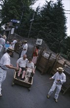 PORTUGAL, Madeira, Monte , Tourists starting their Toboggan ride down to Funchal guided by two