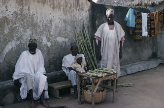 NIGERIA, Plateau, Three traditionally dressed men with little girl selling sugar cane from roadside