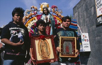 MEXICO, Mexico City, Pilgrims carrying icons and standing in front of statue of the Virgin Mary