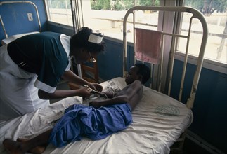 GHANA, Accra, Bedridden child being attended by nurse in children’s ward of Korle-Bu teaching