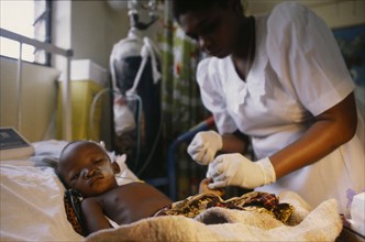 KENYA, Kilifi, Nurse attending critically ill child in malaria research unit.