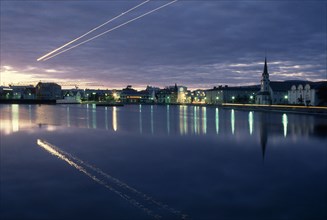 ICELAND, Reykjavik, The Tjörn or lake in city centre at night with light from street lamps