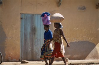 MADAGASCAR, Ambalavao, Two women wearing colourful clothing walking along a street next to a