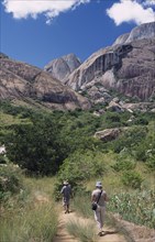 MADAGASCAR, Ambalavao, A tourist being lead by a guide towards rocky mountains and trees in the