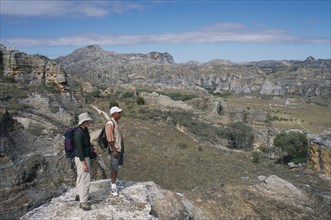 MADAGASCAR, Isalo National Park, Tourist and guide standing on edge of rock looking over craggy